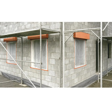 Hausfassade aus Betonsteinen mit Fensterabdeckungen und Baugerüst
