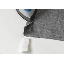 Ein Bügeleisen auf einem grauen Stoff mit Bügelband.