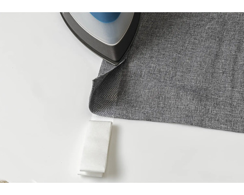 Ein Bügeleisen auf einem grauen Stoff mit Bügelband.