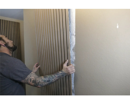 Mann befestigt Akustikpaneele an der Wand zur Schallabsorption und Wandgestaltung.