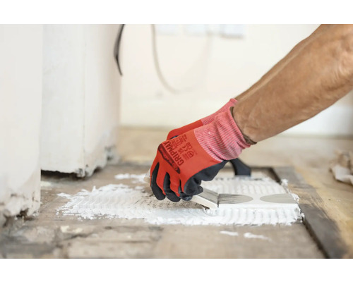 Fliesenleger trägt Klebstoff auf Fliesen auf