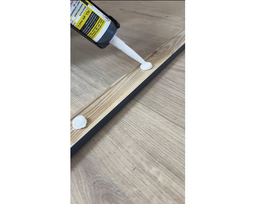 Auftragen von Montagekleber auf eine Holzleiste