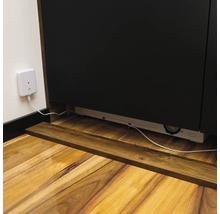 Detailansicht eines Unterbauschranks mit Steckdose und Kabel auf einem Holzboden