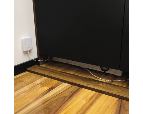 Detailansicht eines Unterbauschranks mit Steckdose und Kabel auf einem Holzboden