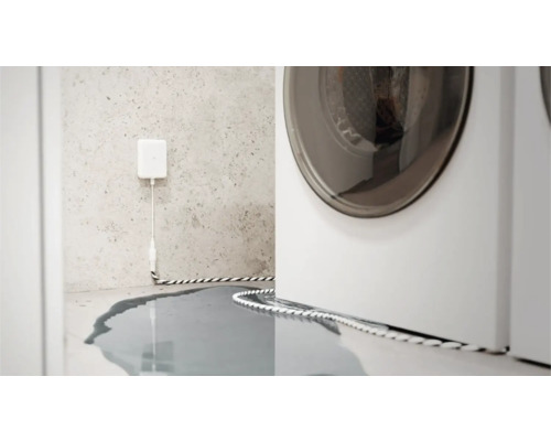 Wassermelder im Einsatz neben einer Waschmaschine, Wasser auf dem Boden