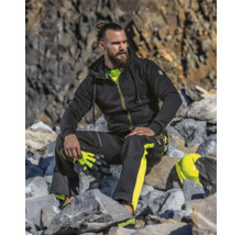 Ein Mann in Arbeitskleidung sitzt auf einem Steinhaufen und hält Handschuhe.