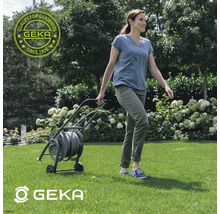 Frau zieht einen Gartenschlauchwagen von Geka über den Rasen