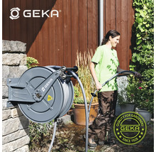 Gartenszene mit aufgerolltem GEKA-Gartenschlauch und einer Frau, die Pflanzen bewässert, GEKA Logo
