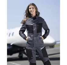 Frau in grauer Arbeitskleidung mit Jacke und Hose vor einem Flugzeug