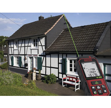 Ein Laser-Entfernungsmesser misst die Dachhöhe eines Hauses