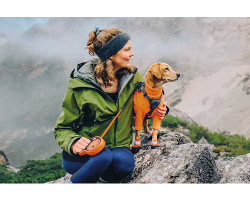 Frau mit Hund in Wanderkleidung auf einem Felsen