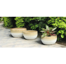 Drei Pflanzgefäße aus Keramik im Garten.