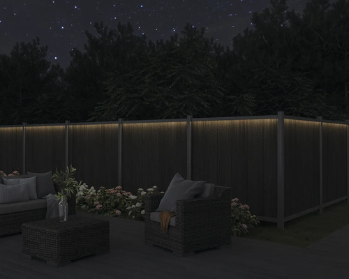 Gartenmöbel auf Terrasse mit beleuchtetem Zaun bei Nacht