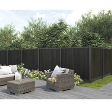 Gartenszene mit dunklem Sichtschutzzaun, Loungemöbeln und Bepflanzung