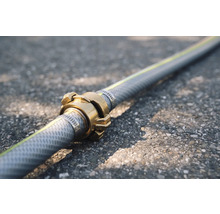 Gartenschlauch mit Messingkupplung auf Asphalt