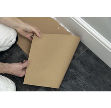 Handwerker schützt mit Abdeckpapier den Boden vor Farbspritzern