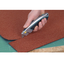 Ein Teppich wird mit einem Teppichmesser zugeschnitten.