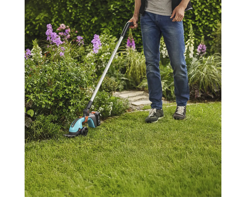 Mann verwendet Akku-Grasschere mit Stiel im Garten