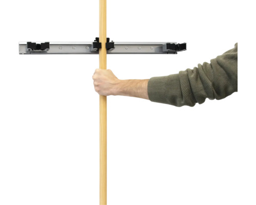 Mann befestigt Stiel in Wandhalterung für Werkzeuge