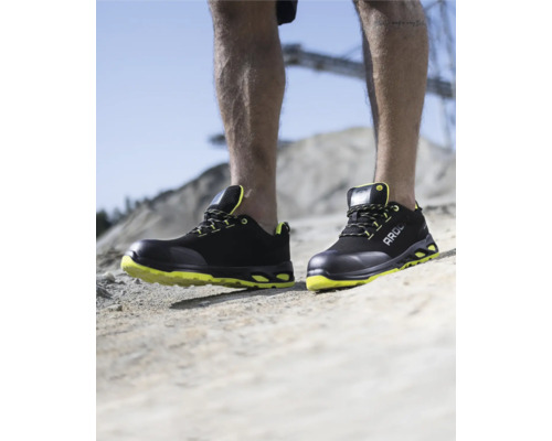 Person trägt schwarze und gelbe Sicherheitsschuhe.