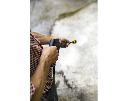 Eine Person reinigt eine Betonoberfläche mit einem Hochdruckreiniger.