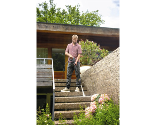 Mann reinigt Treppe mit Hochdruckreiniger im Außenbereich.