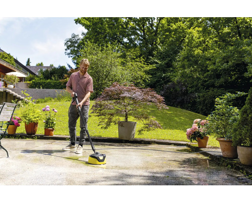 Mann reinigt Terrasse mit Flächenreiniger