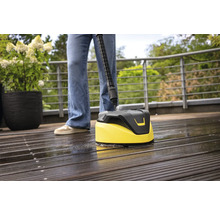 Person reinigt Holzterrasse mit einem Oberflächenreiniger.