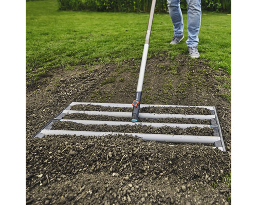 Bodenbearbeitung mit einer Planierschiene im Garten.