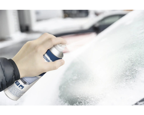 Eine Hand hält eine Sprühdose Enteiser und sprüht auf eine vereiste Windschutzscheibe.