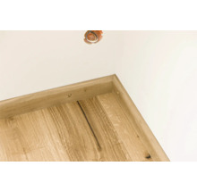 Ecke eines Zimmers mit Holzfußleiste und Steckdose in der Wand