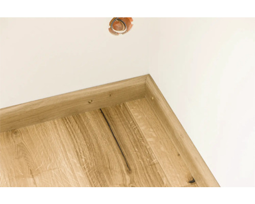 Ecke eines Zimmers mit Holzfußleiste und Steckdose in der Wand