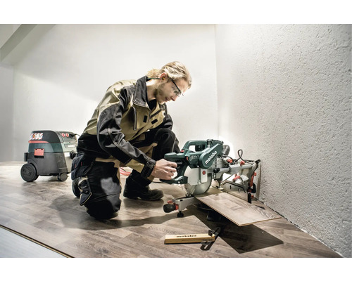 Handwerker mit Metabo Kapp- und Gehrungssäge beim Laminat schneiden in einem Raum.