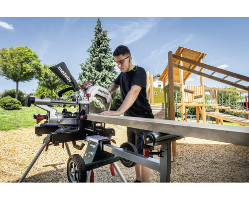 Mann sägt Holzbrett mit Metabo Kapp- und Gehrungssäge im Garten