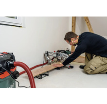 Ein Handwerker sägt ein Holzbrett mit einer Metabo Kappsäge in einer hellen Werkstatt.