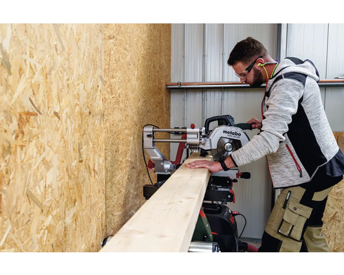 Ein Mann schneidet ein Holzbrett mit einer Metabo Kapp- und Gehrungssäge.