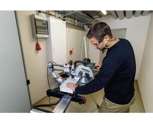 Ein Mann mit Schutzbrille und Gehörschutz arbeitet mit einer Metabo Kappsäge an einem Werkstück.