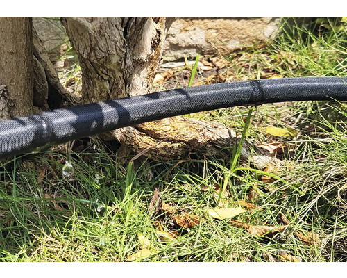 Bewässerungsschlauch im Garten mit austretendem Wasser