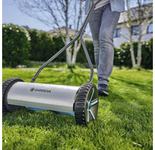 Handrasenmäher mit einer Person im Garten.