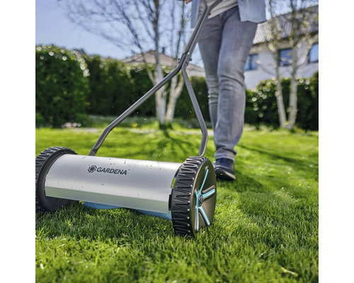 Handrasenmäher mit einer Person im Garten.