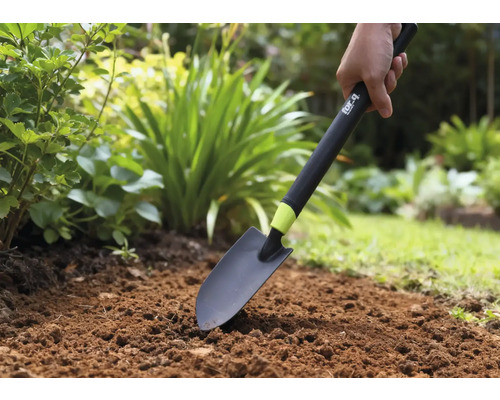 Person verwendet eine Gartenschaufel im Gartenbeet.