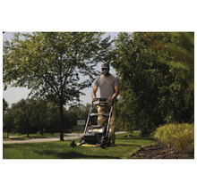 Ein Mann mäht mit einem Rasenmäher den Rasen in einem Garten.