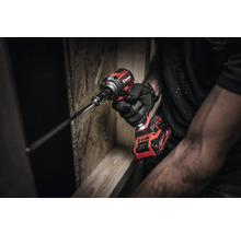 Ein Mann mit Handschuhen hält einen Einhell Akku-Schlagschrauber beim Schrauben in Holz.