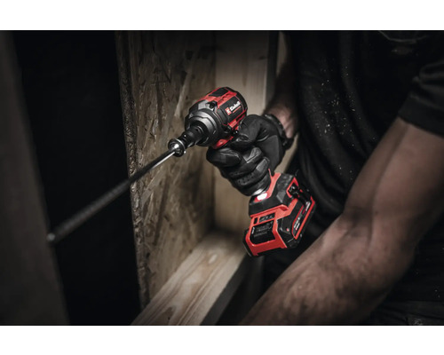 Ein Mann mit Handschuhen hält einen Einhell Akku-Schlagschrauber beim Schrauben in Holz.