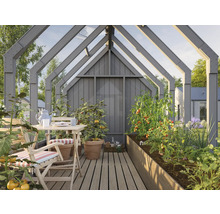 Gewächshaus mit Tisch, Stühlen und bepflanzten Hochbeeten