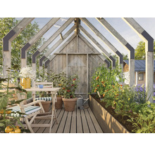 Gewächshaus mit Holzkonstruktion, Tisch, Stühlen und bepflanzten Beeten