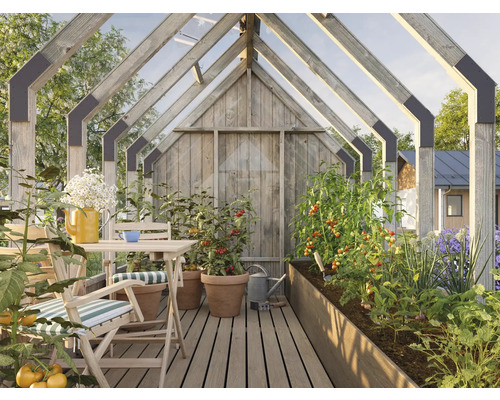 Gewächshaus mit Holzkonstruktion, Tisch, Stühlen und bepflanzten Beeten
