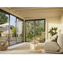 Helles Wohnzimmer mit Sofa, Sessel, Teppich und Blick durch die Glasschiebetüren in den Garten.