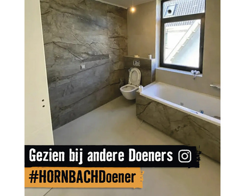 Badezimmer mit Badewanne und Toilette mit grauer Marmoroptik