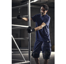 Mann in Arbeitskleidung bedient ein Baugerüst.